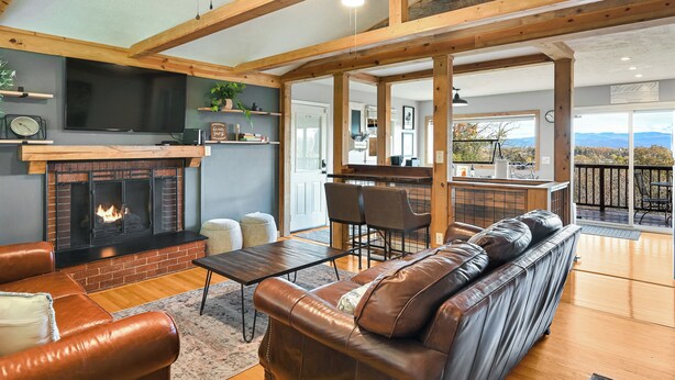 A spacious living room with a fireplace, leather sofa, and a dining area.