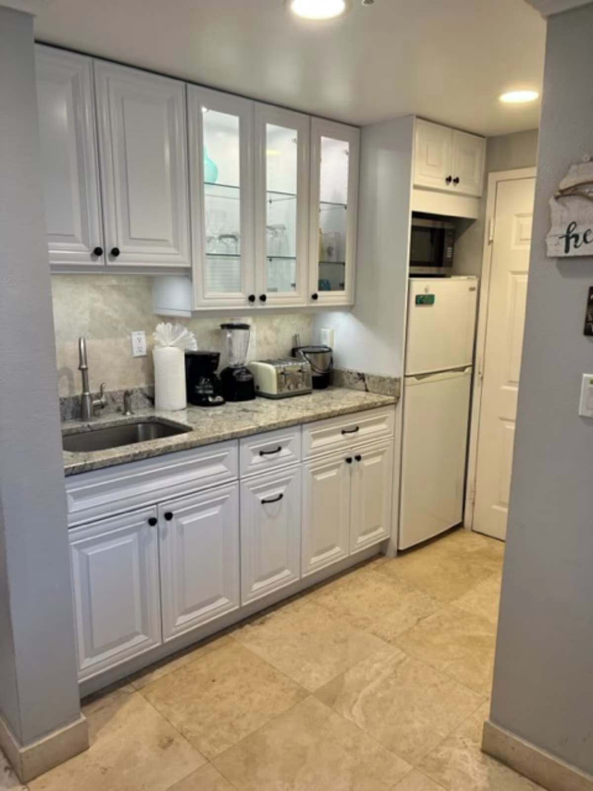 A kitchen with white cabinets, a sink, a toaster, and a refrigerator.