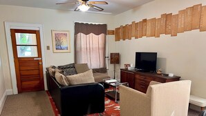 Una sala de estar con sofá, sillón, televisor y una pared con placas de identificación.