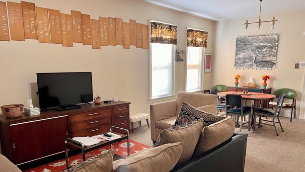 Una sala de estar con televisión, muebles de madera, un sofá y un comedor con mesa y sillas.
