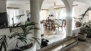 A spacious living area with a dining table, chairs, and potted plants.
