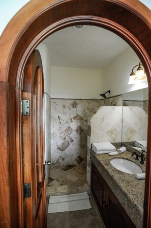 Une salle de bain avec une porte en bois, un lavabo, un miroir et un espace douche.