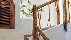 A staircase with wooden railings and a view of a plant through a window.