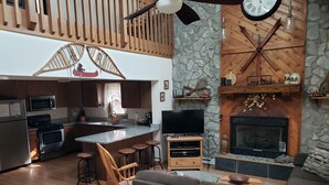 Eine moderne Küche mit einer zentralen Kochinsel, Holzelementen und einer Wand aus Naturstein.