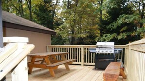 Eine Holzterrasse mit Picknicktisch und Grill.