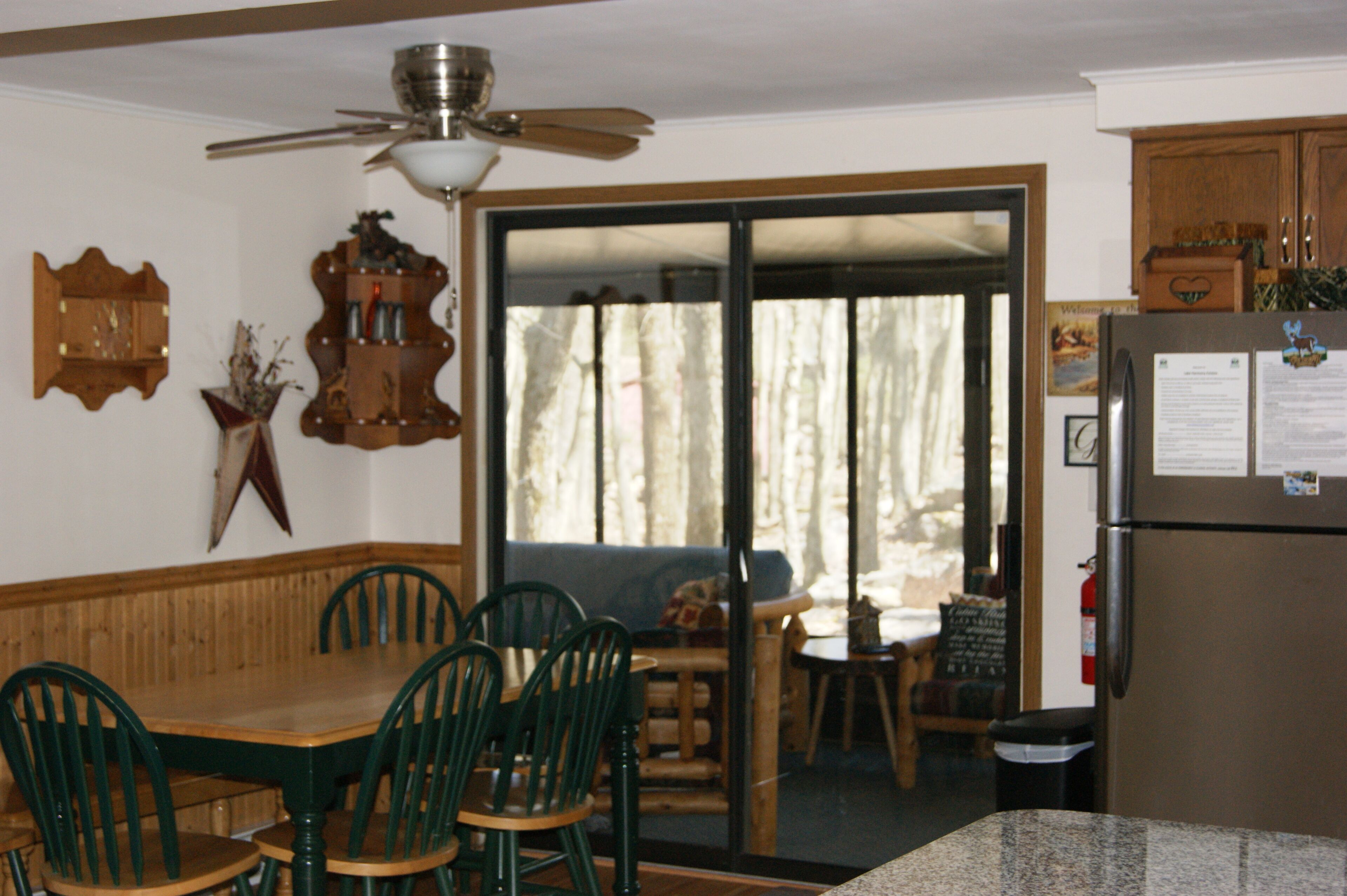 Zona pranzo con tavolo e sedie in legno, una ventola a soffitto e un frigorifero.