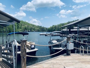 A dock with boats, a wooden pier, and a forested hillside in the background.