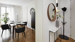 Un coin repas doté d’un parquet en bois disposé en motif à chevrons, d’une table à manger pour quatre personnes et de chaises noires.
