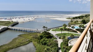 Un complexe hôtelier de bord de mer doté d’un pont menant à la plage, d’une piscine et offrant une vue sur l’océan.