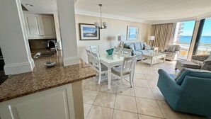 Un salon moderne comprenant un coin repas, une cuisine et un balcon avec vue sur la mer.