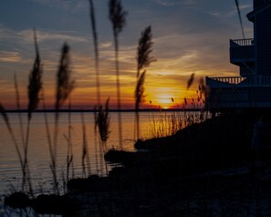 A sunset view with a building on the right and tall grasses in the foreground. - Waterfront Townhouse!  Gorgeous Sunsets!  2 Decks on Water! (Ocean City)