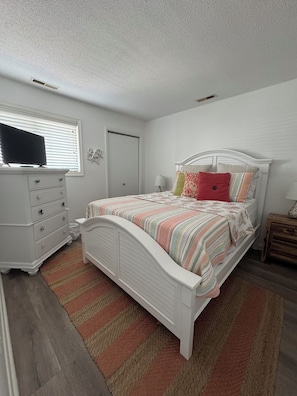 Un dormitorio con cama, cómoda y televisor sobre un mueble.
