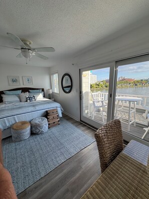 A bedroom with a bed, a ceiling fan, a window, and a view of a balcony with outdoor furniture. - Waterfront Townhouse! Gorgeous Sunsets! 2 Decks on Water! (Ocean City)