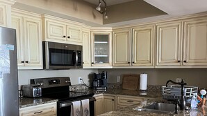 A kitchen with granite countertops, stainless steel appliances, and cream-colored cabinetry. - Oceanfront Condo - Fantastic Views, Beautiful Furnishings!  (Folly Beach)