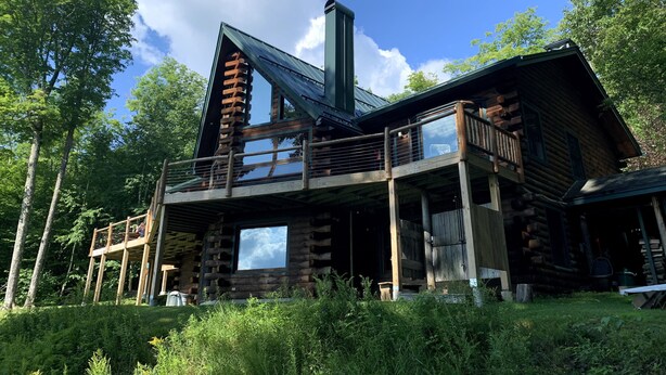 Une cabane en rondins dotée d’un balcon et d’une cheminée.