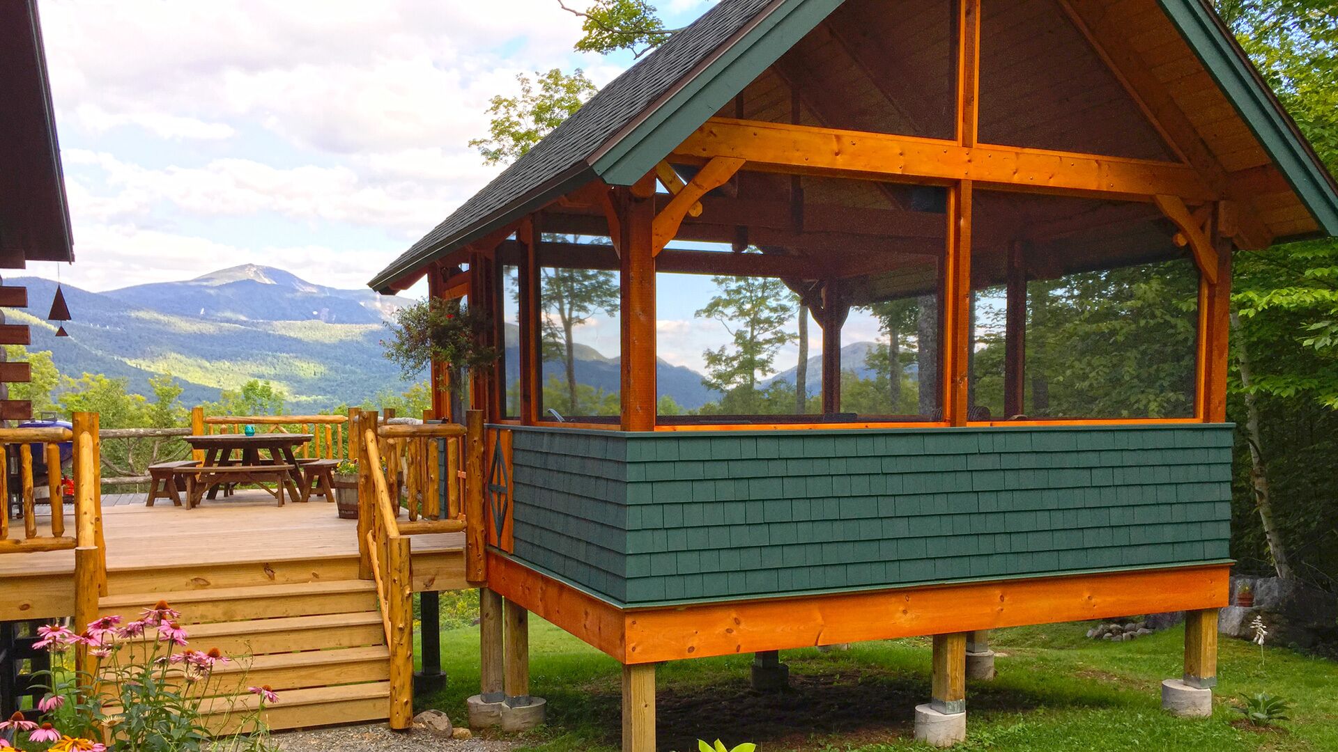 Una cabana de fusta amb un porxo cobert i vistes a les muntanyes.