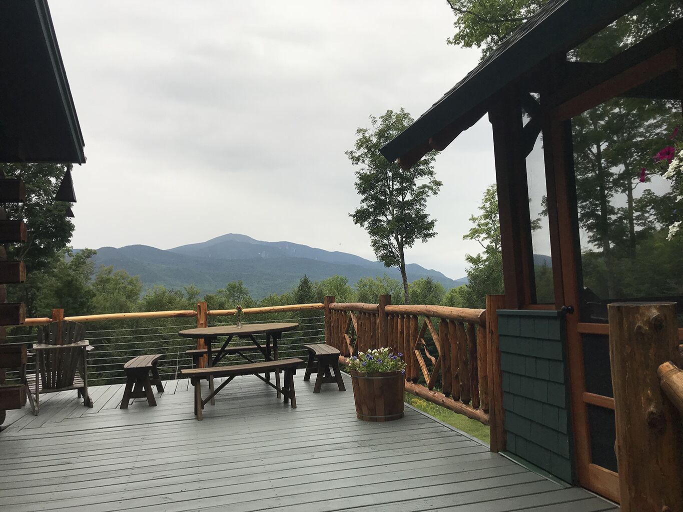 A wooden deck with picnic tables and a view of mountains.