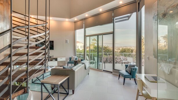 A modern interior with a spiral staircase, a balcony with outdoor seating, and large windows offering a city view. - Renovated Mid-Century Mod Home with Spectacular Views in Point Loma (Spa & A/C) (San Diego)