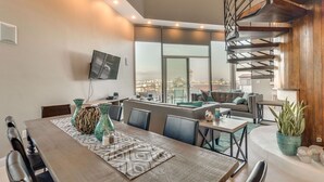 A modern dining area with a large table, chairs, and a TV mounted on the wall. - Renovated Mid-Century Mod Home with Spectacular Views in Point Loma (Spa & A/C) (San Diego)