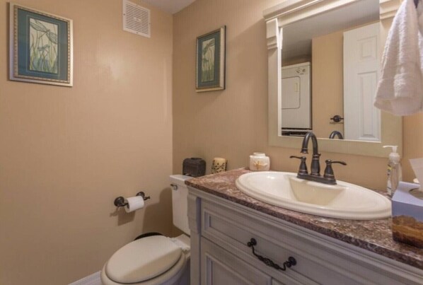 Ein Badezimmer mit Toilette, Waschbecken mit Spiegel und zwei Bilder an der Wand.
