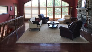 A spacious living room with a high ceiling, large windows, and a fireplace. - PICKLEBALL, Heated Pool, Game Room, Outdoor Oasis, Tennis, Basketball, & woods! (Griggsville)