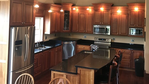 A spacious kitchen with wooden cabinets, stainless steel appliances, and a central island. - PICKLEBALL, Heated Pool, Game Room, Outdoor Oasis, Tennis, Basketball, & woods! (Griggsville)