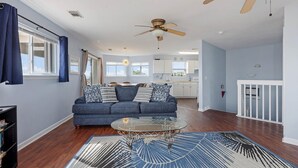 Ein Wohnzimmer mit einem blauen Sofa, einem Glastisch und einem gemusterten Teppich.