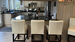 Una cocina moderna con una isla central, armarios empotrados y una zona de estar con sillas.