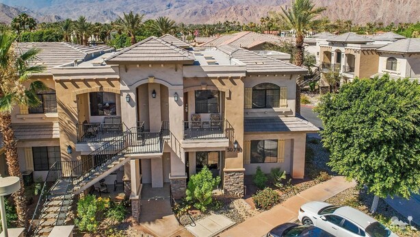 A multi-story residential building with a central courtyard, balconies, and a view of mountains.