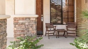 A patio with a stone pillar, a wooden door, and a window with a view of trees.