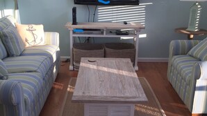A living room with striped sofas, a wooden coffee table, a TV, and a lamp.