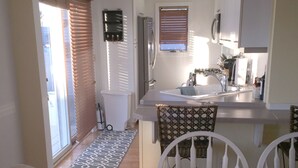 A compact kitchen with a dining area, white furniture, and a ceiling fan.