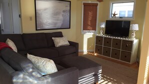 A living room with a dark brown sofa, a television on a white cabinet, and a ceiling fan.