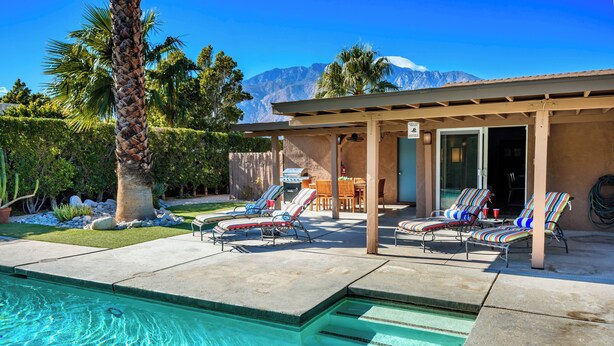 A pool area with lounge chairs, a covered patio, and a mountain view. - Charming Family Friendly Home with Heated Pool.   (Palm Springs)