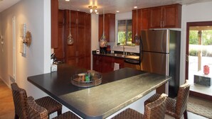 A modern kitchen with a central island, stainless steel appliances, and wooden cabinets. - Charming Family Friendly Home with Heated Pool.   (Palm Springs)