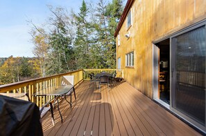 Eine Holzterrasse mit Tisch und Stühlen mit Blick auf ein bewaldetes Gebiet.