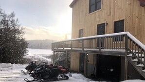 Un edificio de madera con balcón y zona techada para motos de nieve.