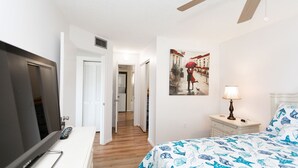 Une chambre d’hôtel avec un lit, une télévision, un bureau et un tableau au mur.