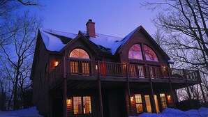 A large, two-story log cabin with a balcony and large windows, surrounded by snow. - Wildlife Surrounds! Enjoy Fireplace, Pool Table, Fire Pit, Piano. Near Marina! (Galena)