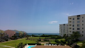 Ein Hotel mit Schwimmbad, Meerblick und einem gepflegten Rasen.