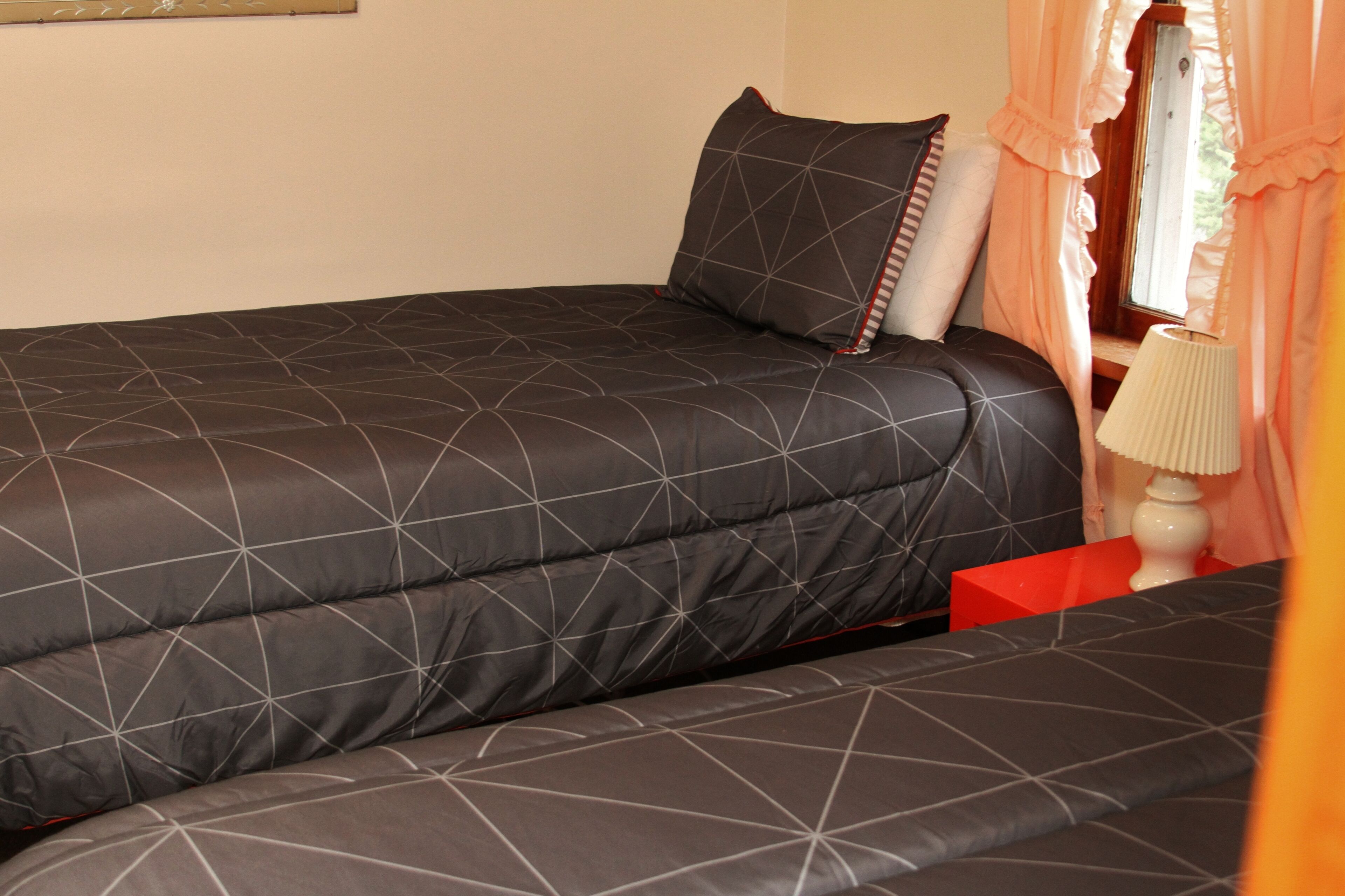 A bedroom with a large bed, a bedside table, and a window with curtains.