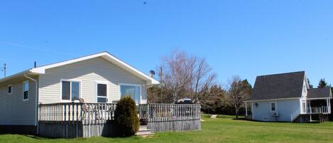 A single-story house with a fenced yard and a small tree in front.