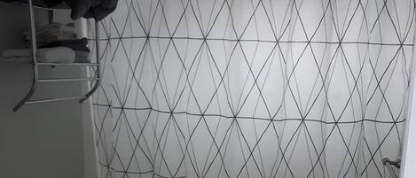 Ein Badezimmer mit Duschvorhang mit geometrischem Muster, Toilette und Marmorwaschbecken.