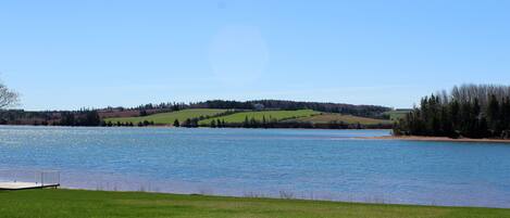 A lake with a dock, surrounded by green hills and trees.