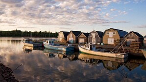 A calm harbor with several wooden boats docked and a row of small buildings, likely used for storage or as a fishery. - 2 bedroom, A/C, Sleeps 6 (New London)