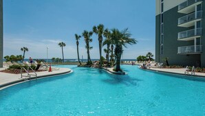 Ein Swimmingpool mit Palmen, Liegestühlen und einem Gebäude mit Balkonen.