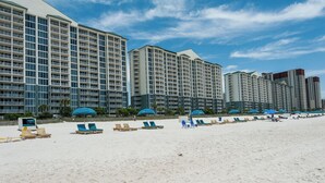 Ein Hotel direkt am Strand mit mehreren Hochhäusern, Strandstühlen und Liegen.