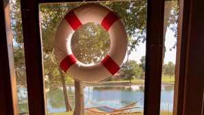 Una porta con un salvagente appeso al vetro, vista su un lago e un'amaca.