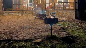 Una baita con veranda, posti a sedere all'aperto e un braciere.
