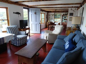 A cozy living room with a sofa, armchairs, a wooden coffee table, and a television.